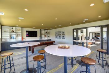 Community Clubhouse Game Room with Round Desk, Stools, Chess Set, Mounted Flatscreen Television at Addison Ranch Apartments, California